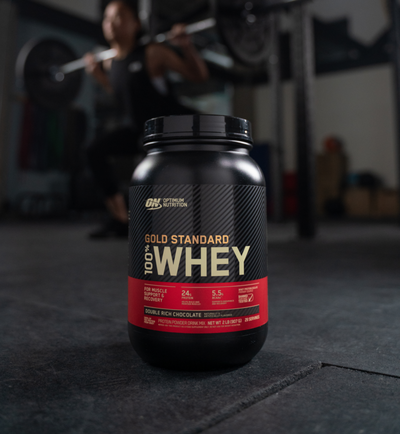 a tub of optimum nutrition gold standard 100% whey with woman in background