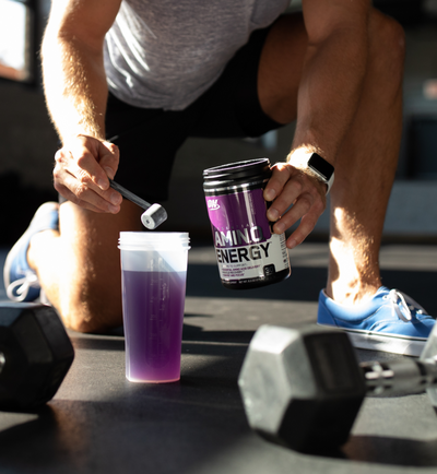 a man putting a scoop of amino energy in shaker