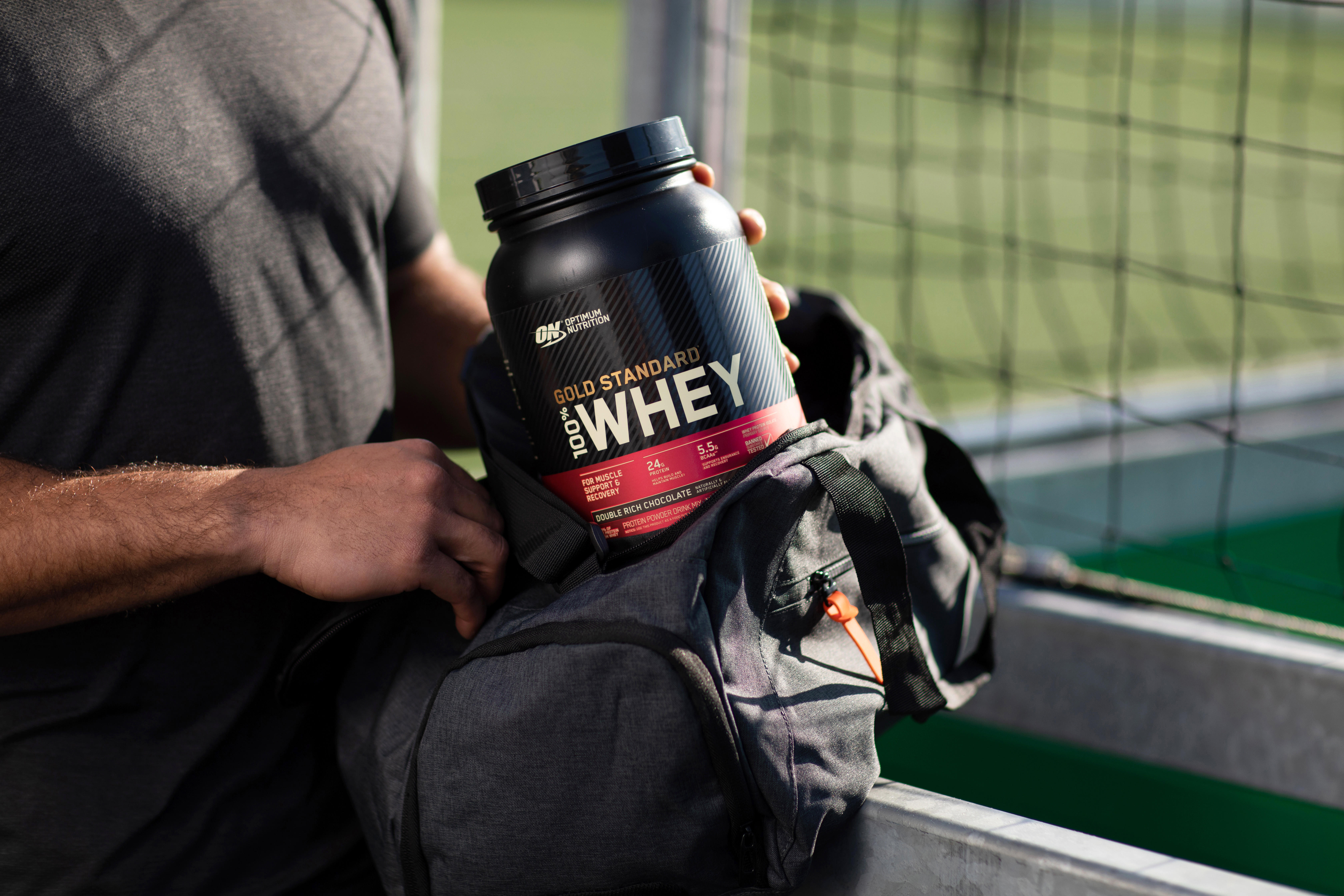 Man putting Optimum Nutrition Gold Standard Whey tub in his gym bag