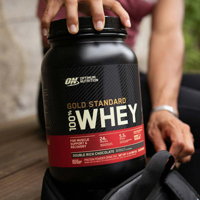 a man holding a tub of optimum nutrition gold standard 100% whey protein