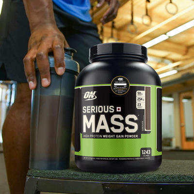 tub of optimum nutrition serious mass with a man training behind the tub