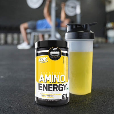 tub of optimum nutrition amino energy with a man training behind the tub
