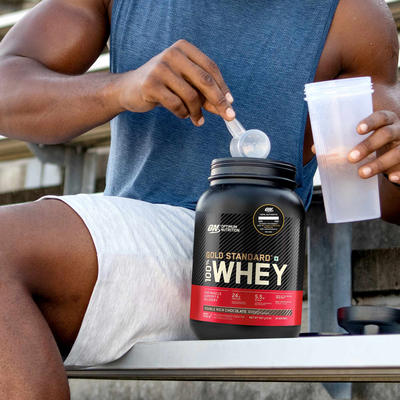 man filling up his shaker with gold standard 100% whey